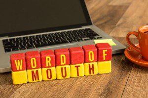 Word of Mouth written on a wooden cube in a office desk